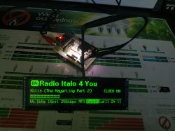 ESP32 module connected to a custom PCB, displaying radio information on a large green screen.