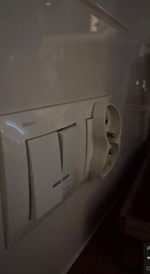 Gniazdko elektryczne i włączniki na ścianie.