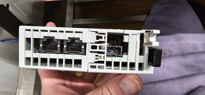 Close-up of a module rear panel with two RJ45 ports and a power connector, held in a hand.