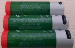 AA USB Rechargeable Lithium-Ion Batteries Three green AA lithium-ion batteries with multilingual labels, lying on a light background.