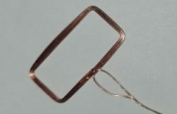 Rectangular copper wire frame with a thin twisted wire on a light background