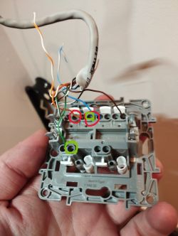 Zbliżenie na tylną część przełącznika elektrycznego z odsłoniętymi przewodami.