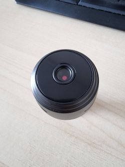 Small black Wi-Fi camera on a wooden desk.