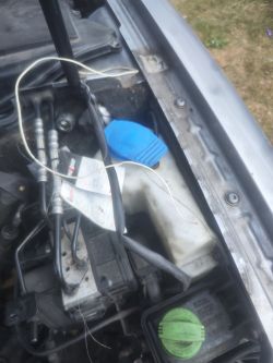 Zbliżenie na komorę silnika Audi A4 B6 z widoczną częścią pompy ABS, przewodami i pojedynczym białym kablem.