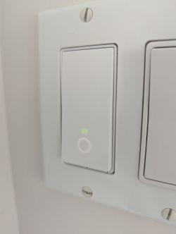Wall switch turned on with green wifi LED and glowing white circle.