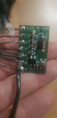 Płytka elektroniczna trzymana w ręku z widocznymi rezystorami i przewodami lutowanymi.