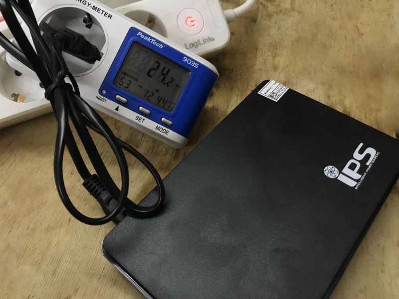 IPS mini UPS on a table next to a PeakTech 9035 power meter and power strip