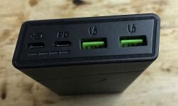 Zbliżenie na gniazda powerbanku z dwoma zielonymi portami USB i jednym portem USB-C.