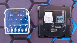 Two circuit boards: a blue PCB with pins and a black board with modules and a QR code