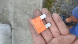 Pomarańczowy przepalony bezpiecznik 40A trzymany w dłoni.