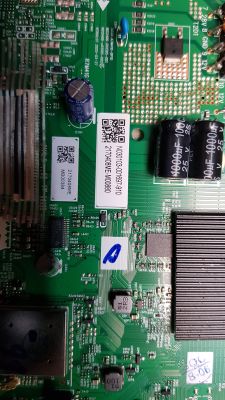Zdjęcie zielonej płytki drukowanej z elementami elektronicznymi, takimi jak kondensatory, cewki i chipy. Na płytce znajdują się kody QR oraz oznaczenia i opisy techniczne.