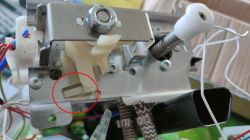 Zbliżenie na wewnętrzny mechanizm ekspresu do kawy z zaznaczonym czerwonym kółkiem mikrostykiem.