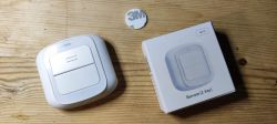 Wireless two-key switch and its box on a wooden surface.