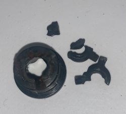 Uszkodzona część sprzęgła do młynka do kawy Smeg z fragmentami obok