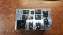 A circuit board with several transistors and electronic components on a wooden background.