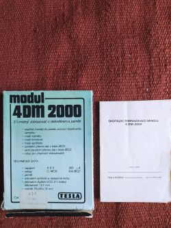 Opakowanie modułu wyświetlacza TESLA 4DM 2000 i broszura informacyjna na tle tkaniny
