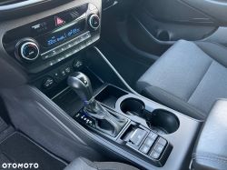 Car center console with automatic gear shifter, cup holders, and climate control panel.