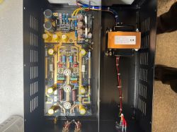 Widok wnętrza urządzenia elektronicznego z płytką drukowaną i transformatorem.