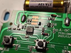 Close-up of a green circuit board with buttons, battery, and BOiL chip