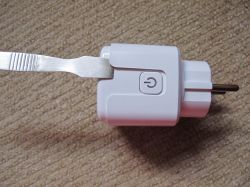 Opening a Smart Plug with a Tool Smart plug with a metal tool used for opening it.