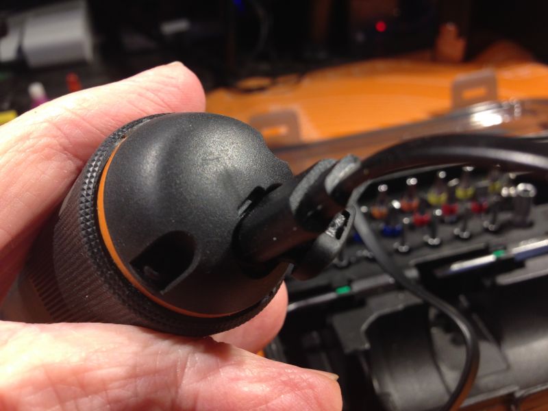 Osoba trzymająca wkrętak elektryczny z kablem USB-C z zestawem bitów w tle.