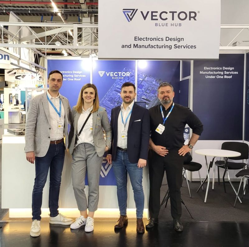 Cztery osoby stojące przed stoiskiem VECTOR Blue Hub na targach Embedded World 2024.