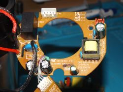 Obwód drukowany z różnymi komponentami elektronicznymi, w tym transformatorem i kondensatorami.