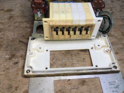 Disassembled module with digit switches and wires on a workbench, with housing parts nearby