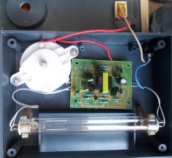 Wnętrze urządzenia elektronicznego z płytką drukowaną i podłączonymi kablami.