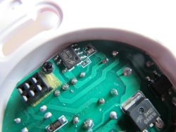 Close-up of an electronic device's PCB with visible integrated circuits and a pin header.