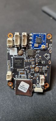 Płytka drukowana z komponentami elektronicznymi na tle szarego materiału.