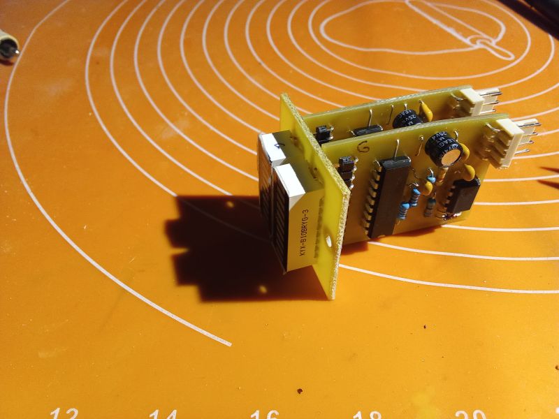 Printed circuit board with electronic components on an orange background.
