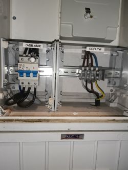 Zdjęcie rozdzielnicy elektrycznej z oznaczeniami ZASILANIE i ODPŁYW.