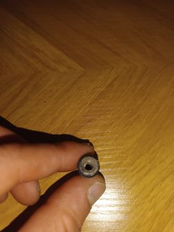 Osoba trzyma mały cylindryczny element z otworem na środku.