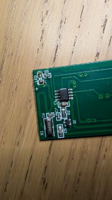 Close-up of a PCB with SMD components and an IC chip on a wooden surface