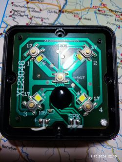 Urządzenie elektroniczne z widoczną płytką drukowaną i diodami LED na tle mapy.