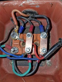 Zbliżenie na podłączenie przewodów wewnątrz skrzynki elektrycznej z zaciskami i kolorowymi kablami.