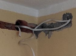 Odkryta instalacja elektryczna w narożniku ściany