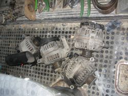 Cztery spalone alternatory ułożone na metalowej powierzchni w warsztacie.