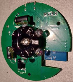 A printed circuit board with electronic components and a central sensor.