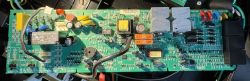 Płytka PCB z elektroniką zasilacza UPS APC ES 550 z widocznymi elementami: transformatorem, bezpiecznikami, kondensatorami i radiatorami.