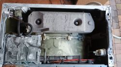 Wnętrze pralki Siemens z widocznym przeciwwagą, przewodami i elementami hydraulicznymi.