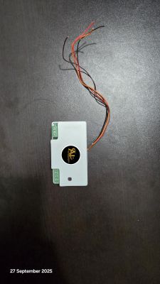 Small electronic module with connectors and exposed wires on a dark surface