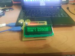 Display showing remote code 0xFD52AD against a laptop background.