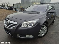 A grey Opel Insignia station wagon parked outdoors next to a sheet metal building.