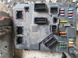 Zdjęcie panelu bezpieczników samochodowych ze złączami elektrycznymi i kolorowymi bezpiecznikami, na którym zaznaczono jedno z gniazd.