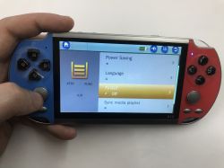 Handheld X12 console in a hand, screen shows settings menu with TV-OUT option