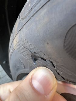 Widoczne pęknięcie na przedniej prawej oponie samochodu.