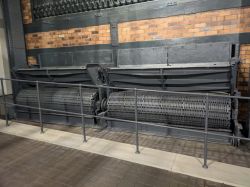 Wnętrze muzeum z przemysłowym urządzeniem na tle ceglanej ściany.