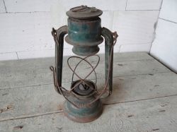 Old, rusted kerosene lamp on a wooden table.